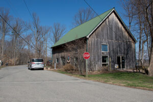 Exterior view of a two-story building with weathered wooden siding and a green peaked roof.
