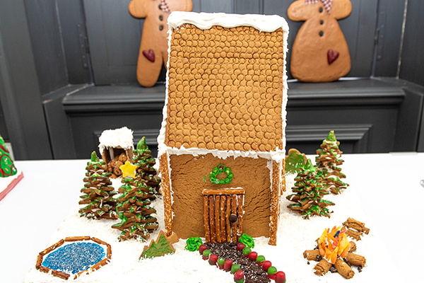 A beautiful gingerbread log cabin with heavy duty pretzel log supports holding up the steep gable roof. This gingerbread home comes complete with fine pretzel furnishings, a big outdoor rolled gingerbread log fireplace, and an inground hot spring pool. There are many cookie trees around to drown out the neighbors envy.