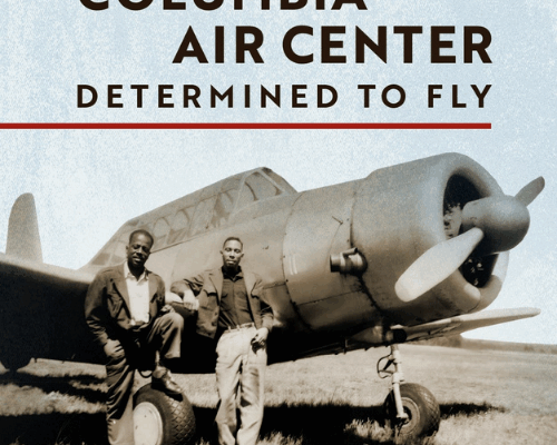 Columbia Air Center - Determined To Fly A black and white image of two men standing in front of an old propeller plane