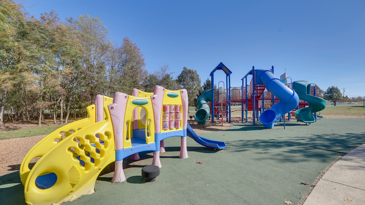 A colorful outdoor playground with multiple play structures featuring slides, steps, platforms, climbing elements, monkey bars, and more.