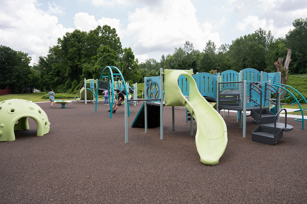 An outdoor playground featuring several large play structures, including slides, swings, platforms, stairs, monkey bars, rope webs, climbing walls, and more.