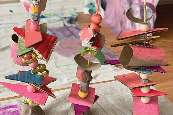 Three sculptures made from mixed media, including wooden sticks, wooden beads, metal nuts and rings, and painted cardboard.