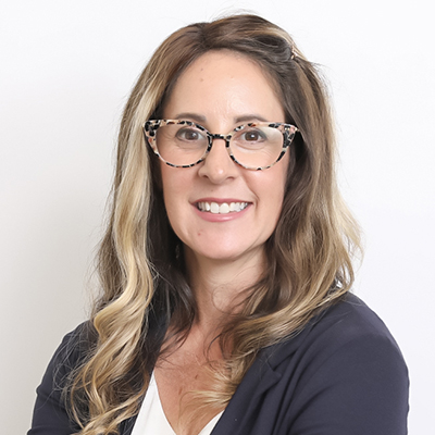 Headshot of a smiling woman with glasses and long hair wearing a dark jacket.